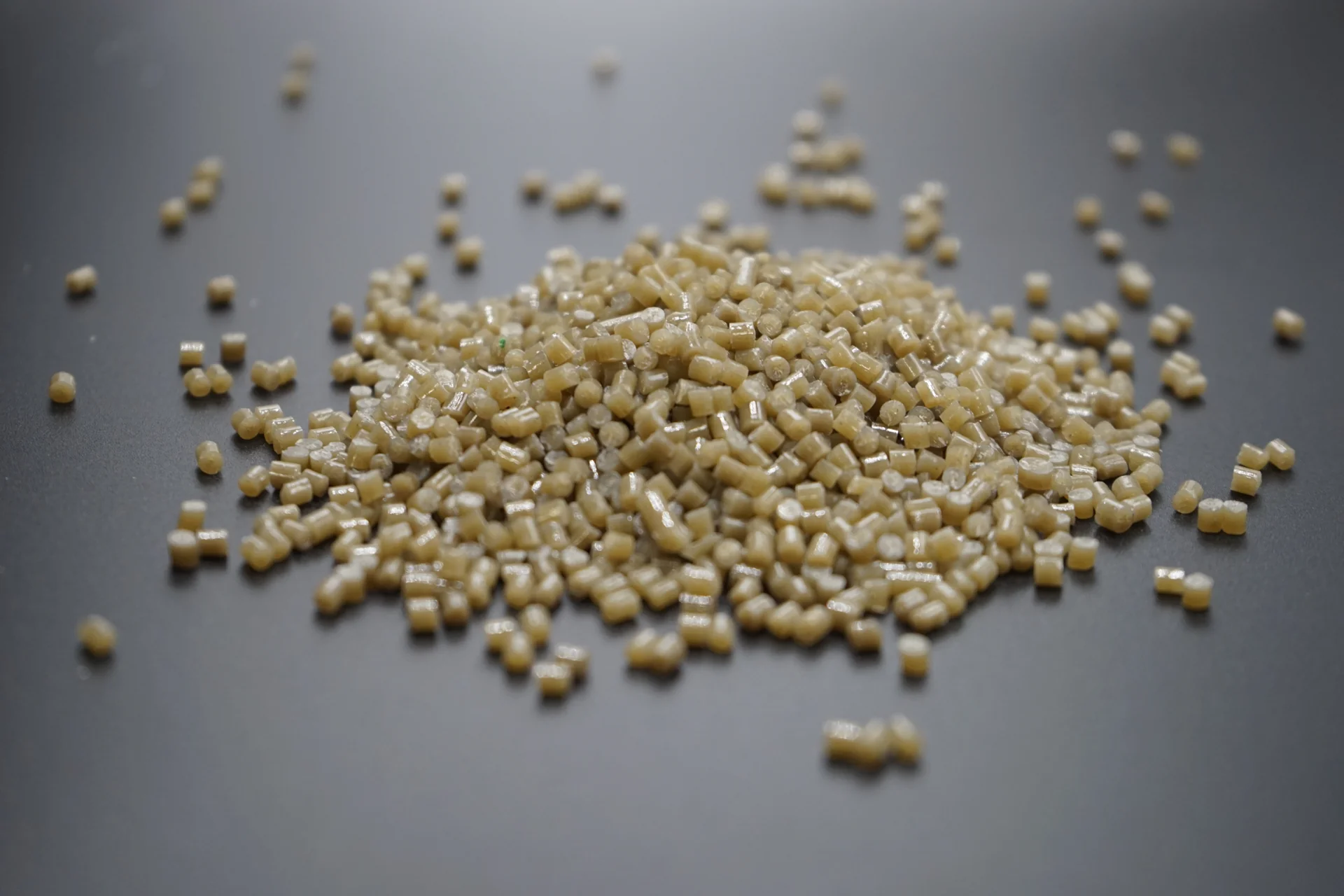 Beige plastic pellets viewed at a low angle on a dark surface