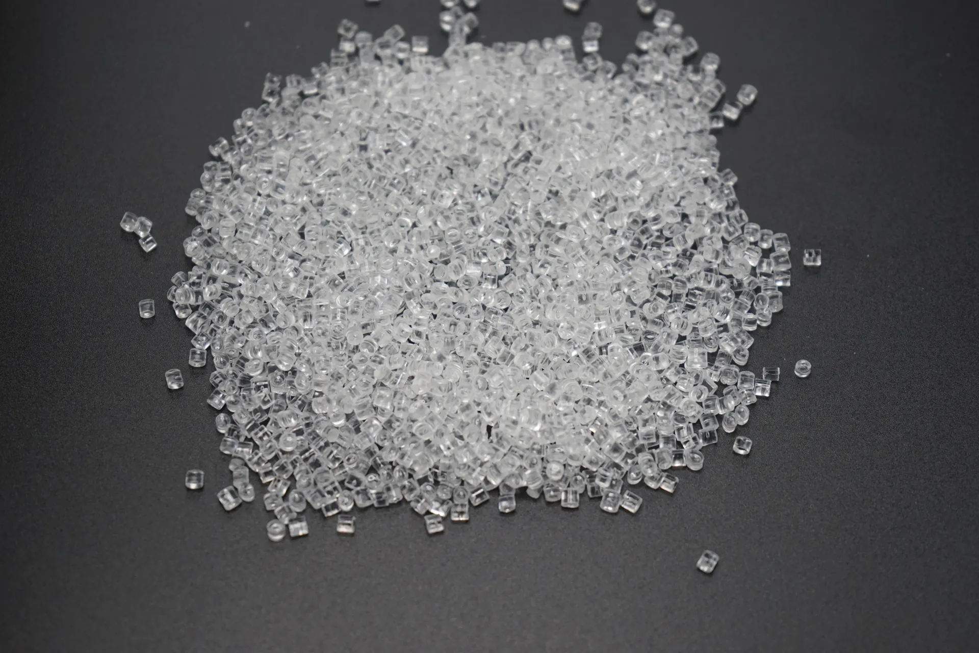Close view of clear plastic pellets on a dark surface