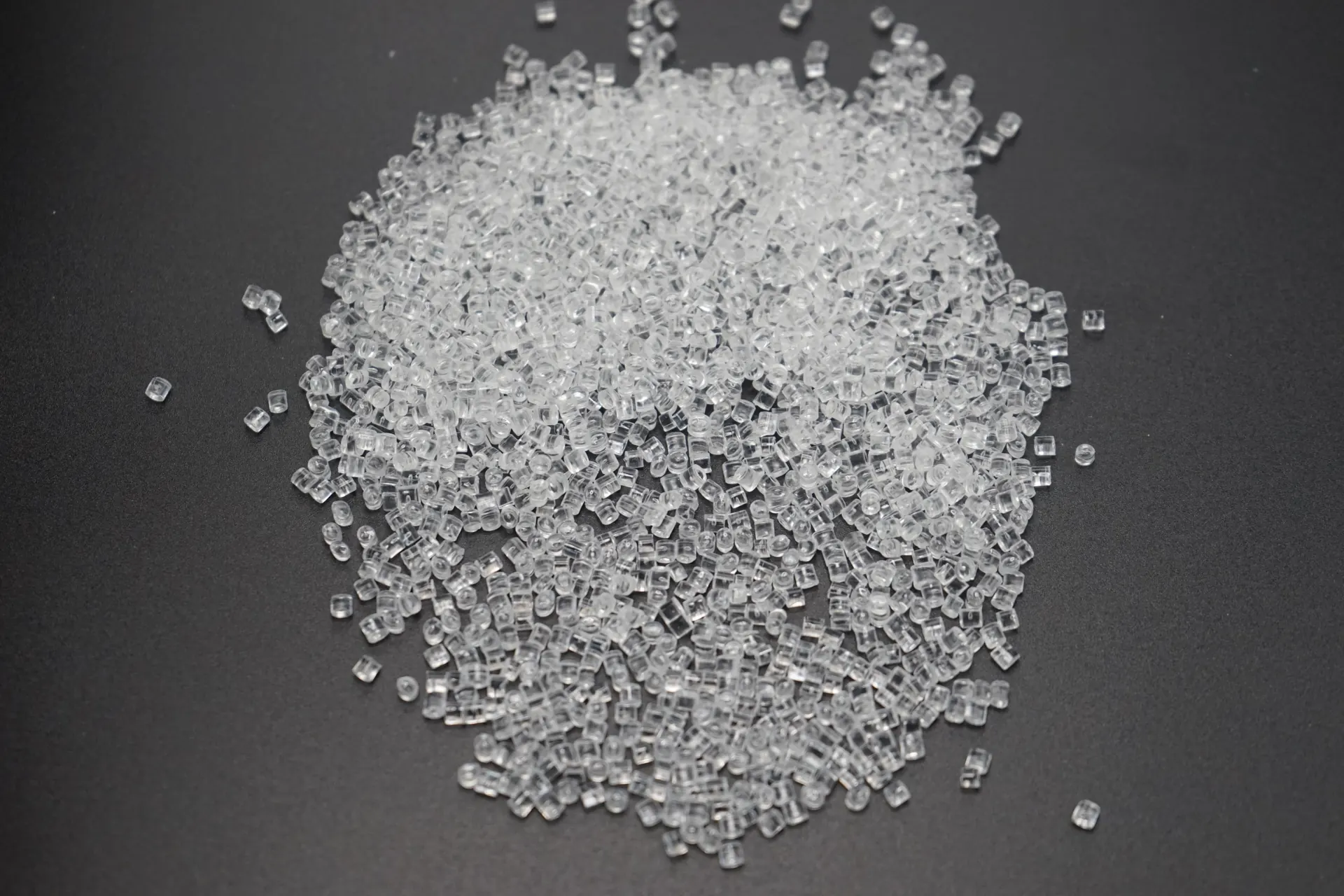 Angled view of clear plastic pellets on a dark surface